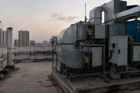 Rooftop plant at dusk: air handling units, control panels and conduit run between them.