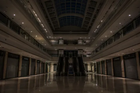 A shopping centre atrium before opening, escalators still and every shopfront shuttered.