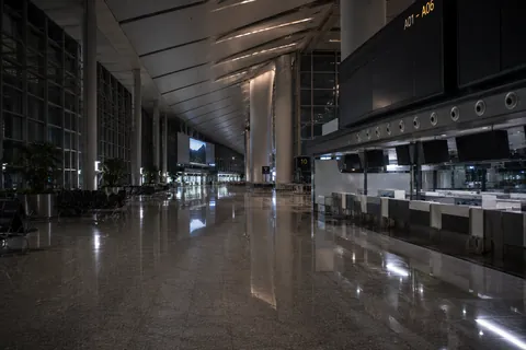 An empty terminal concourse, the check-in counters closed and the floor reflecting the ceiling lights.