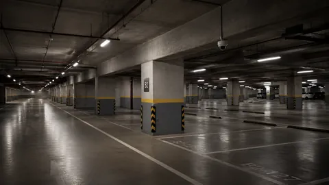 An empty basement car park at night, columns lit down the length of the deck.