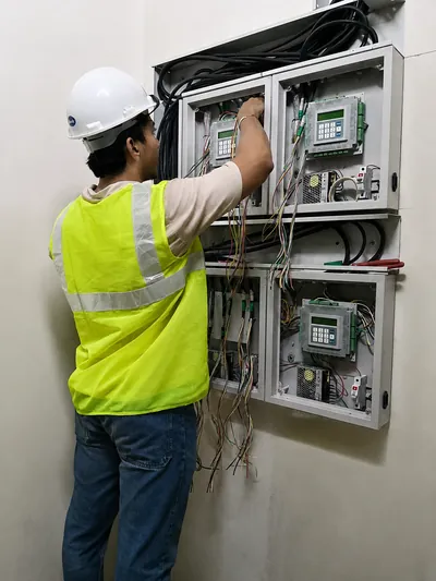 A Concept engineer testing a panel on site, wiring exposed and every device checked rather than sampled.